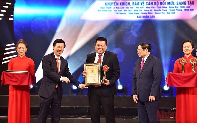 El primer ministro Pham Minh Chinh y el miembro permanente del Secretariado del Comité Central del PCV, Vo Van Thuong entregan el Premio A al representante del grupo de autores del Periódico Nhan Dan.