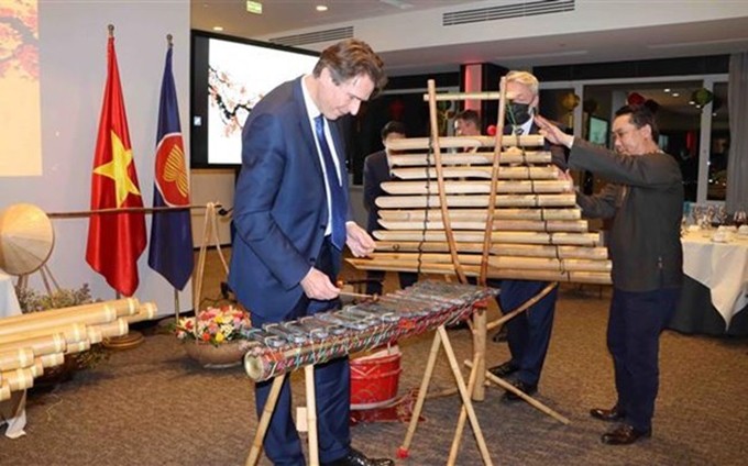 Invitados internacionales prueban tocar instrumentos musicales tradicionales de Vietnam durante el evento. (Fotografía: VNA)