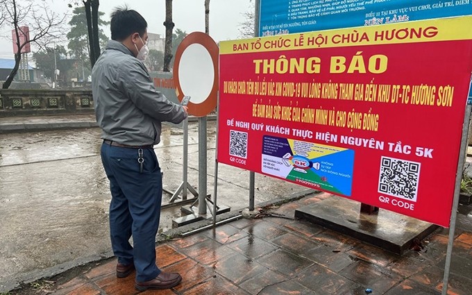 Visitantes escanean el código QR antes de visitar la pagoda Huong.