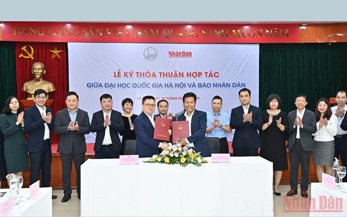 El jefe de redacción del periódico Nhan Dan, Le Quoc Minh y el rector de la Universidad Nacional de Hanói, Le Quan, firman un acuerdo de cooperación. (Fotografía: Nhan Dan)