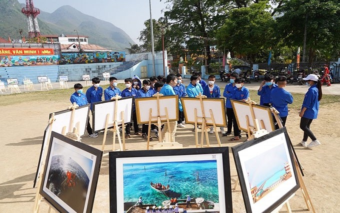 Jóvenes de Ha Giang visitan y escuchan explicaciones sobre el mar y las islas a través de fotografías.