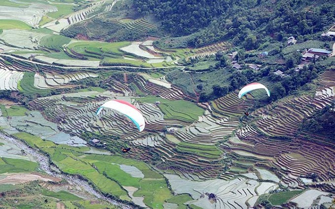 Turistas probando volar en parapente sobre los campos en terrazas en el distrito de Mu Cang Chai, provincia de Yen Bai, durante la temporada de inundaciones. (Fotografía: Nhan Dan)