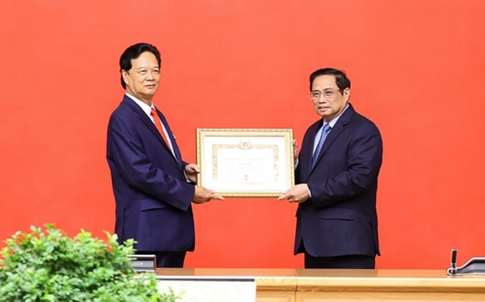 El primer ministro vietnamita, Pham Minh Chinh (D), entrega la insignia a Nguyen Tan Dung (I), exmiembro del Buró Político del Comité Central del Partido Comunista de Vietnam y exjefe del Gobierno. (Fotografía: VNA)