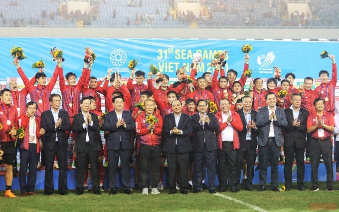 Dirigentes vietnamitas posan junto a otros invitados al escenario y los medallistas de oro en fútbol masculino de los SEA Games 31. (Fotografía: Nhan Dan)