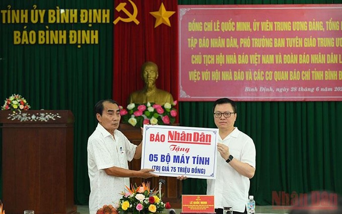 El redactor jefe del periódico Nhan Dan, Le Quoc Minh (derecha), entrega cinco ordenadores a la filial de la APV en Binh Dinh. (Fotografía: Nhan Dan)