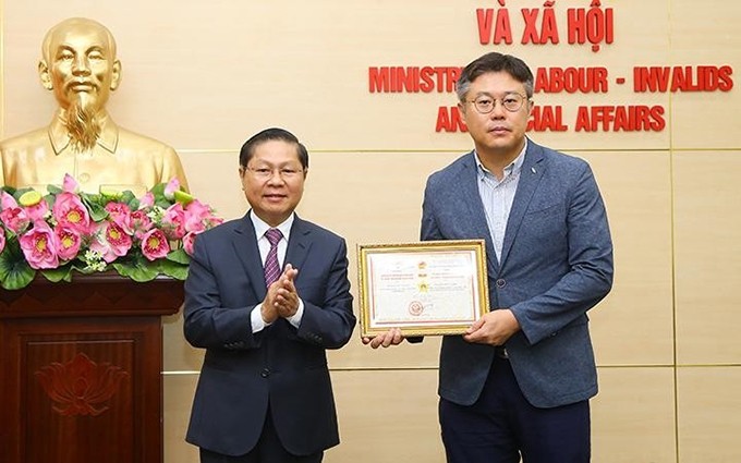 El viceministro de Trabajo, Inválidos de guerra y Asuntos Sociales de Vietnam Le Tan Dung entrega el sello conmemorativo al jefe de la Oficina de Representación de la Agencia Surcoreana para el Desarrollo de Recursos Humanos en Vietnam, Kang Byung Joo.  (Fotografía: Molisa)