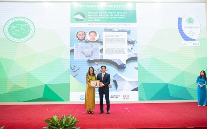 El viceprimer ministro Vu Duc Dam entrega el premio del concurso “Mujeres y el futuro de la economía verde”. (Fotografía: baotainguyenmoitruong.vn)
