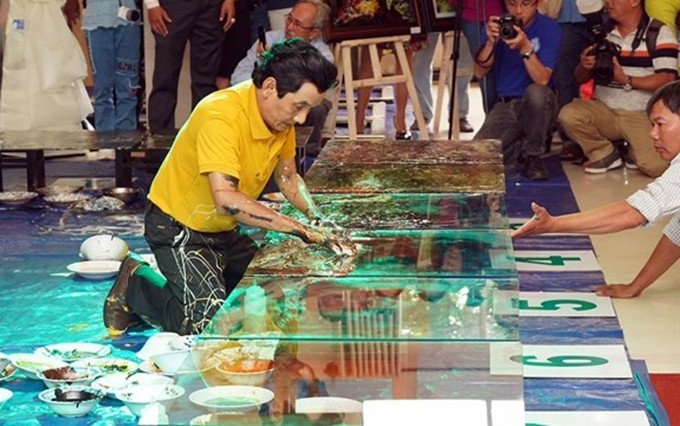 El pintor vietnamita Doan Viet Tien establece récord mundial en la realización de pinturas en reversa sobre vidrio templado. (Fotografia: qdnd.vn)