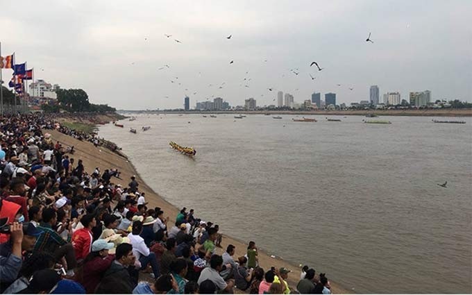 Miles de personas y turistas alientan a los equipos de regatas en el río Tonle Sap.